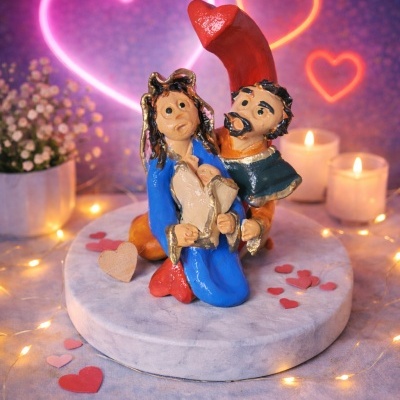 Figura de casal em cerâmica colorida com decoração de corações e velas