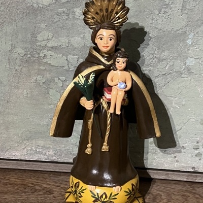 Estatueta de santo com criança em túnica castanha e base amarela decorada