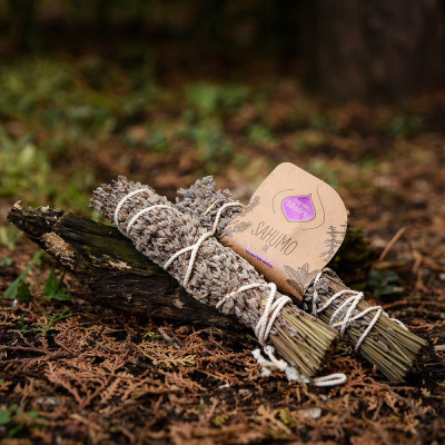 Dois molhos de sálvia seca amarrados com corda, com etiqueta Sahumo de Lavanda, sobre tronco ambiental natural