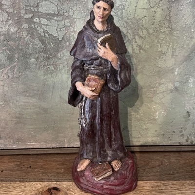 Estátua decorativa de santo com hábito castanho e livros em mãos