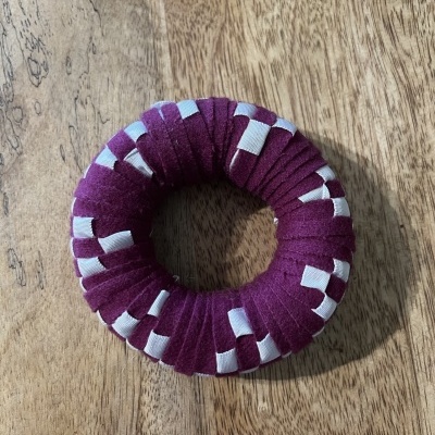 Elástico de cabelo roxo com padrão branco em superfície de madeira