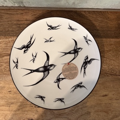 Prato redondo branco com padrão de andorinhas pretas
