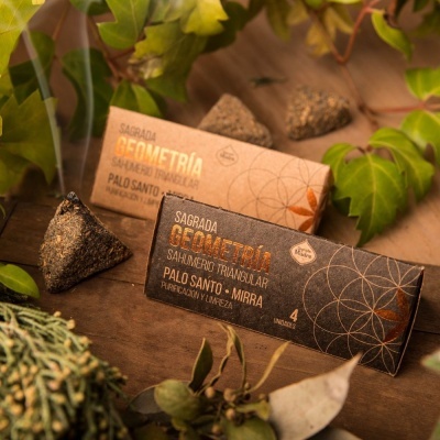 Pacotes de incenso sahumerio triangular SAGRADA GEOMETRIA em preto e bege com folhas e pedras ao redor