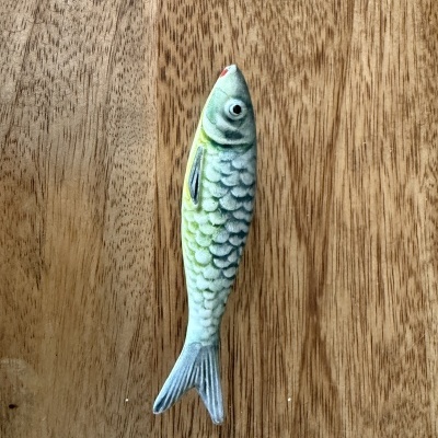 Peixe de brinquedo verde e cinzento sobre madeira clara