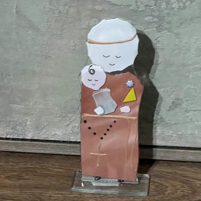 Estatueta de madeira pintada de figura religiosa com criança e terço