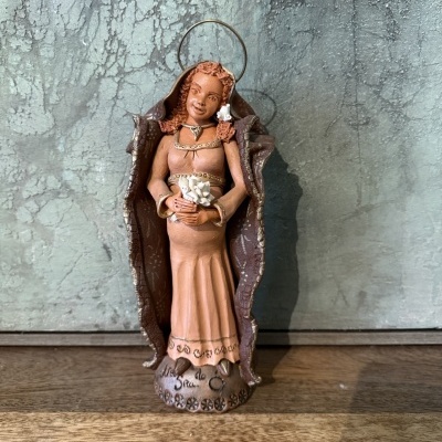 Estatueta de mulher em vestido longo com asas e flores sobre superfície de madeira