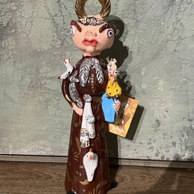 Estatueta decorativa em cerâmica com figura humana e aves coloridas.