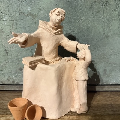 Escultura de barro bege claro com figuras humana e vasos pequenos