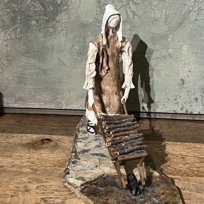 Estátua decorativa de mulher com carrinho de madeira cheia de pedaços de madeira