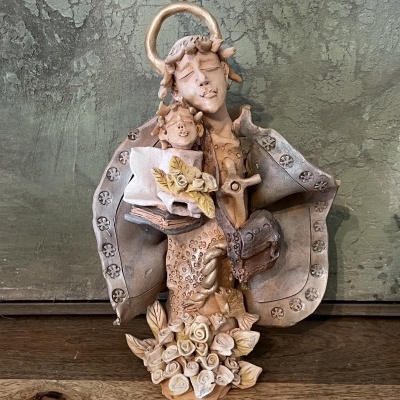 Escultura decorativa religiosa em tons terrosos com criança, cordeiro e flores