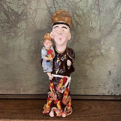 Estátua religiosa colorida em cerâmica de santo com criança em fundo cinzento