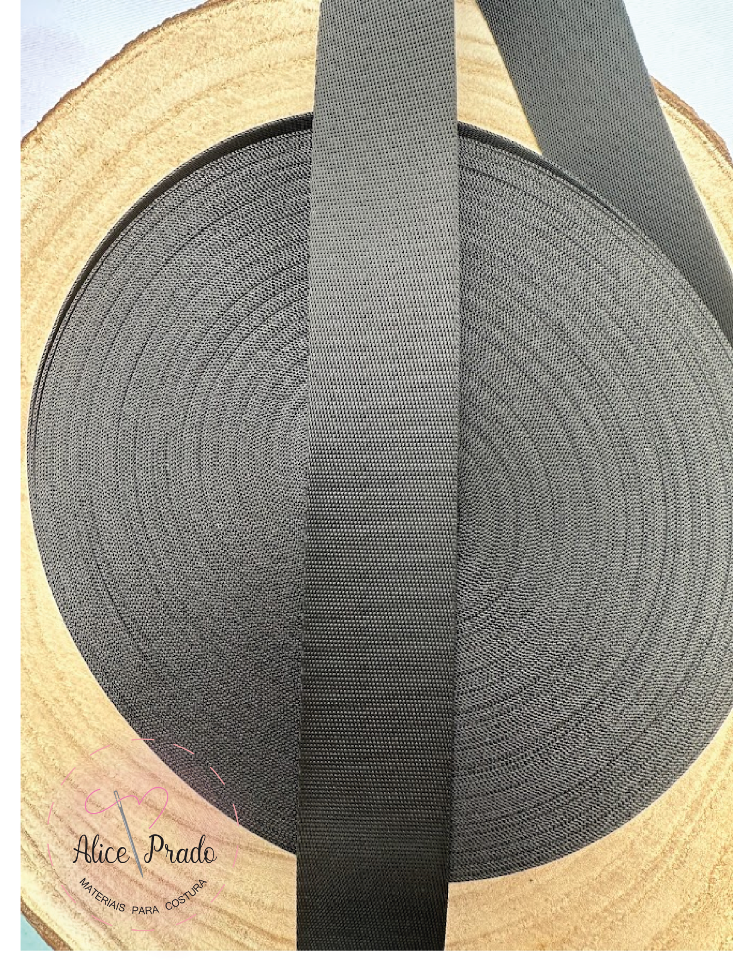 Rolo de fita preta larga sobre madeira clara com selo Alice Prado