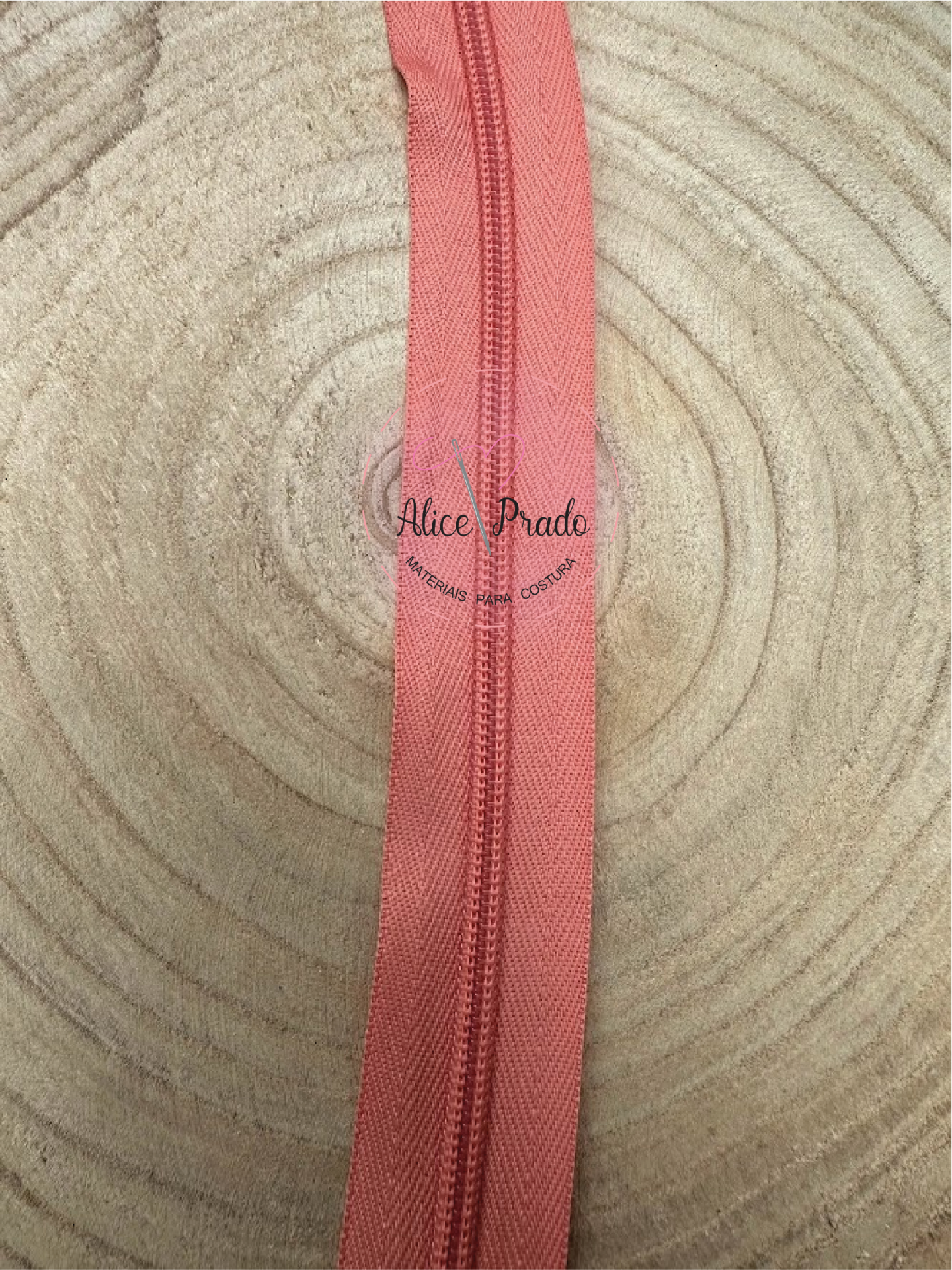 Fecho éclair vermelho coral sobre madeira clara com texto Alice Prado ARTESANIAS PARA COSTURA