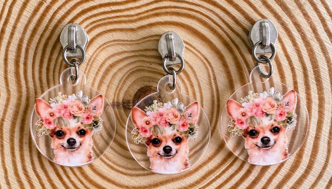 Três porta-chaves com imagem de chihuahuas e coroas de flores sobre madeira