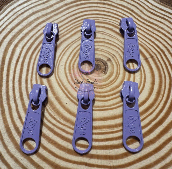 Seis cursores de fecho éclair roxos sobre superfície de madeira com padrão circular