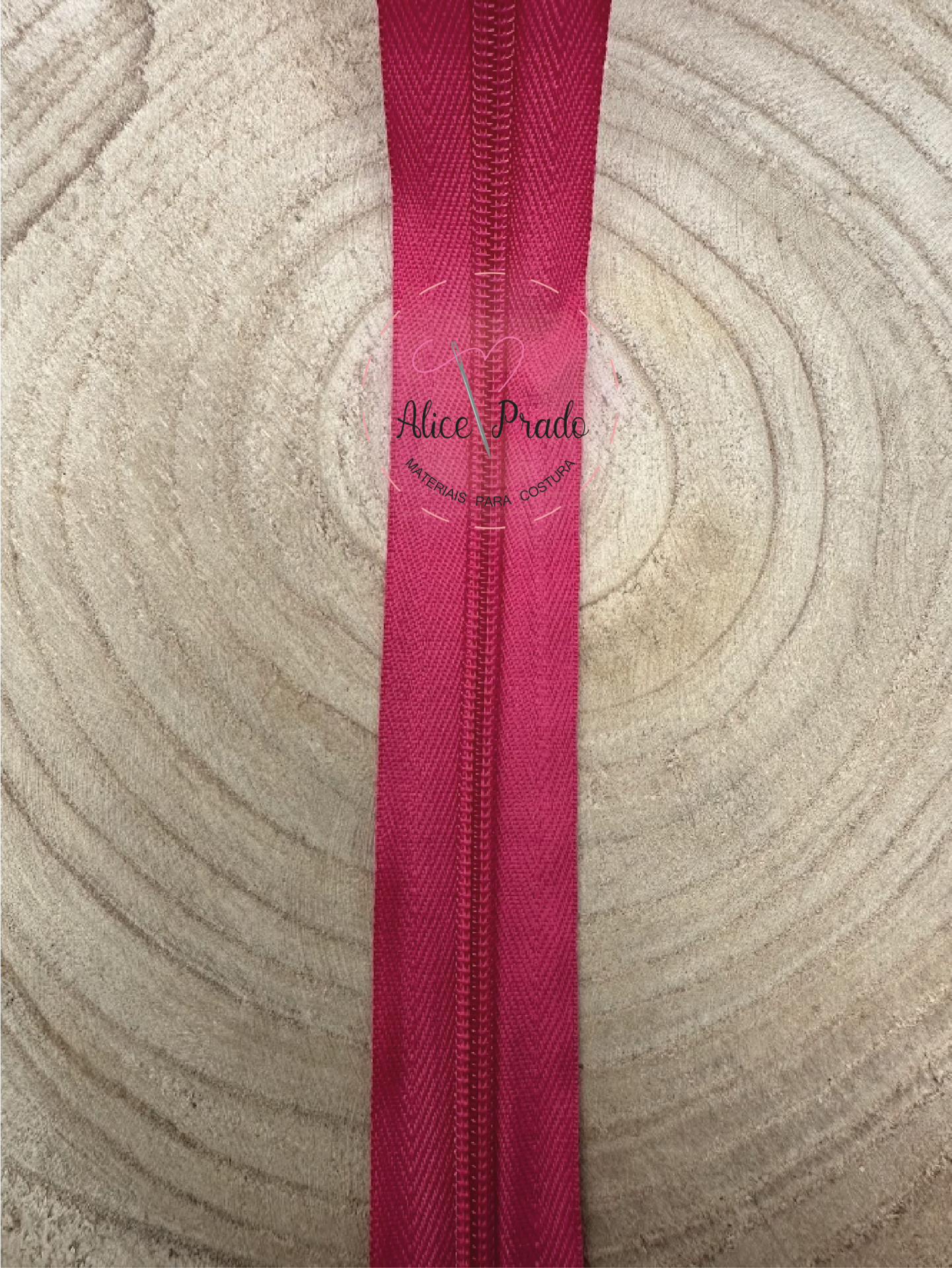 Fecho éclair rosa sobre superfície de madeira clara com anéis de crescimento