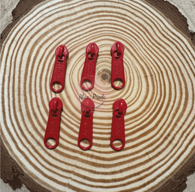 Seis cursoras de zíper vermelhas sobre um fundo de madeira com anéis concentricos