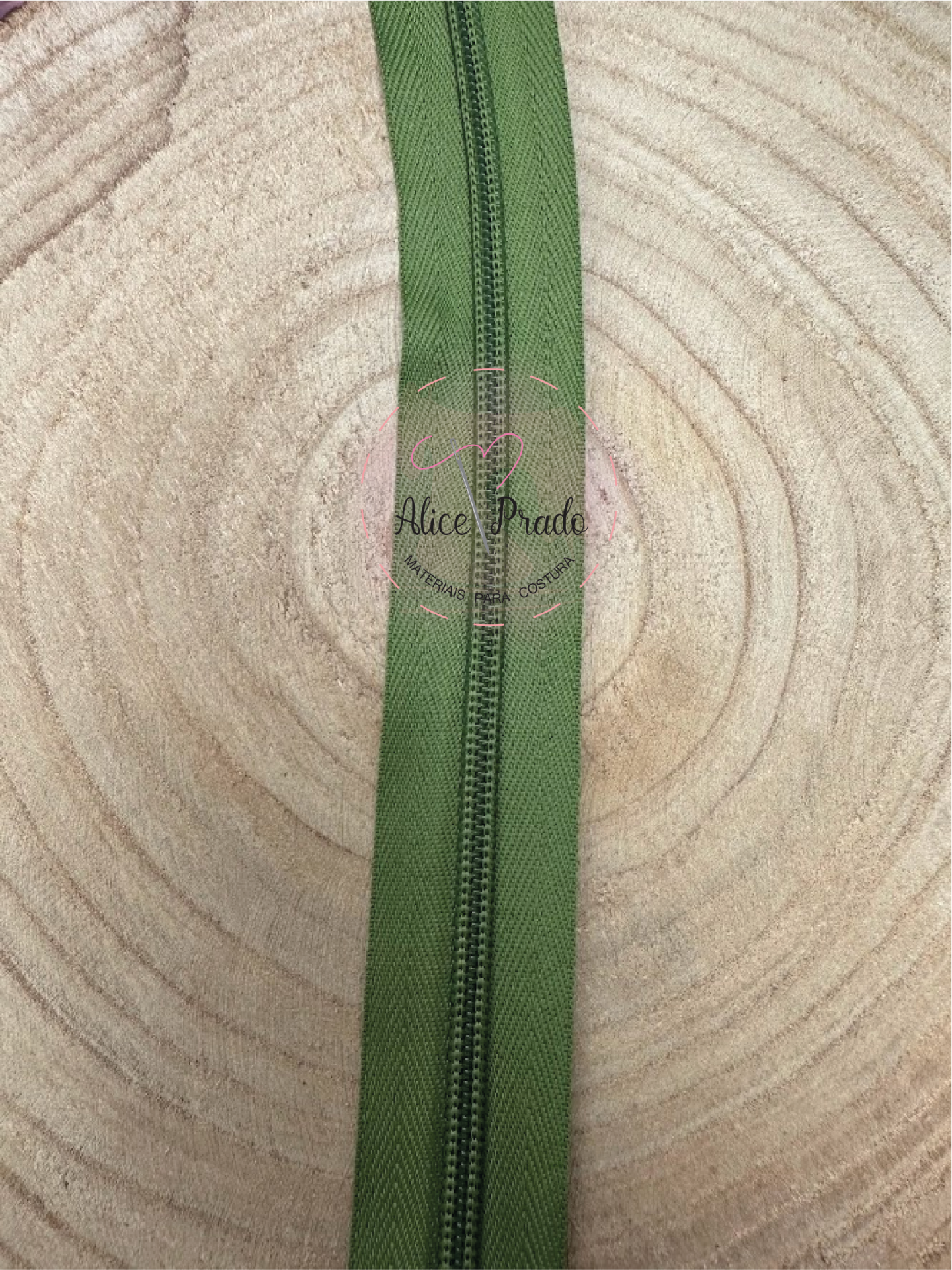 Fecho éclair verde sobre madeira clara com selo vermelho Alice Prado