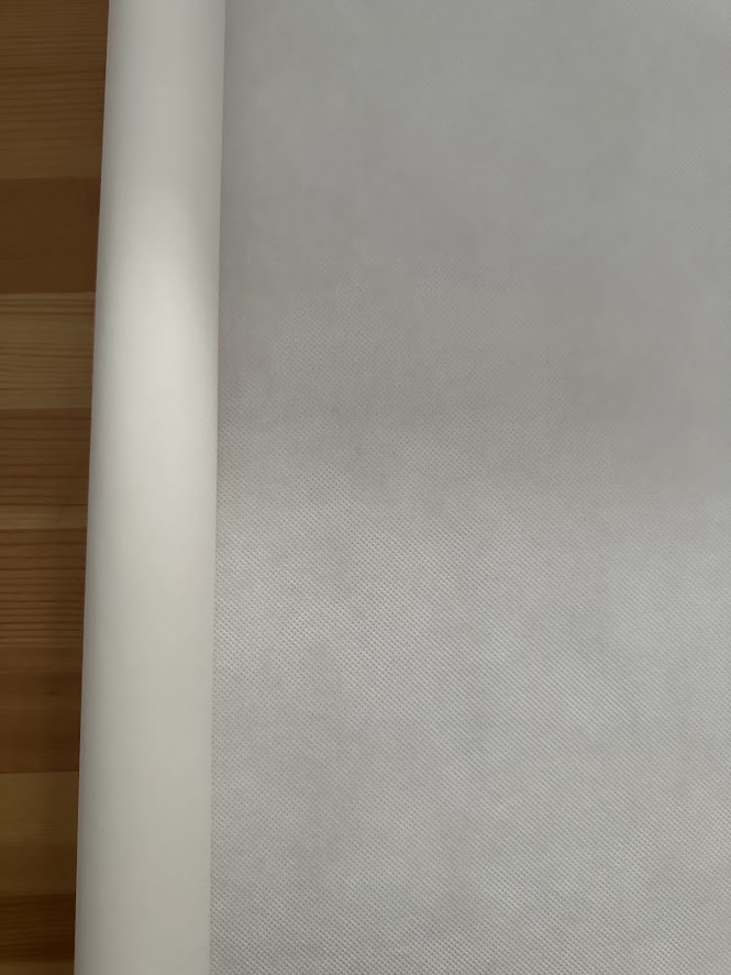 Rolo de papel branco com textura fina sobre superfície de madeira clara