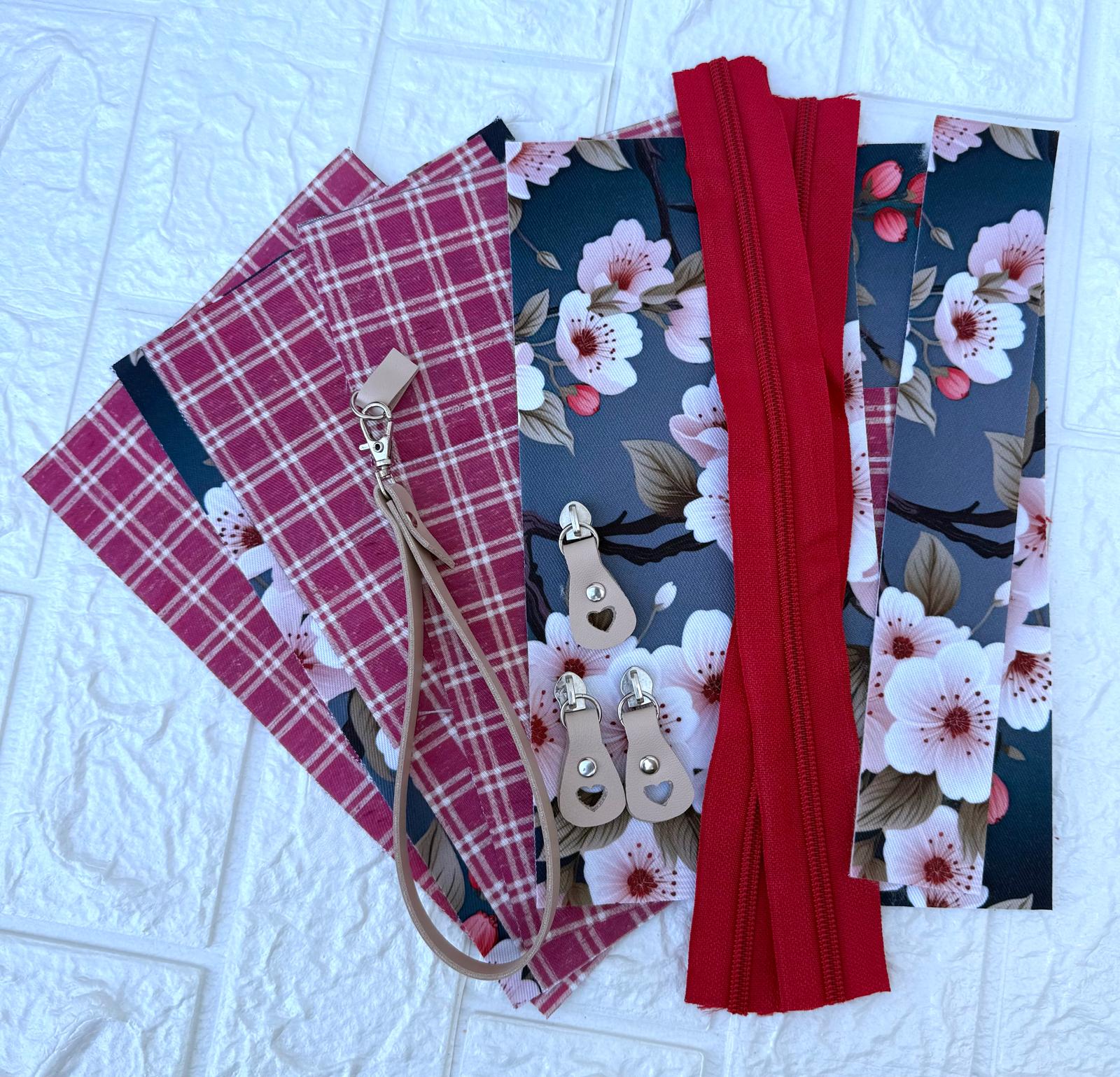 Tecidos florais e xadrez com fecho de correr e puxadores de zíper sobre superfície branca.