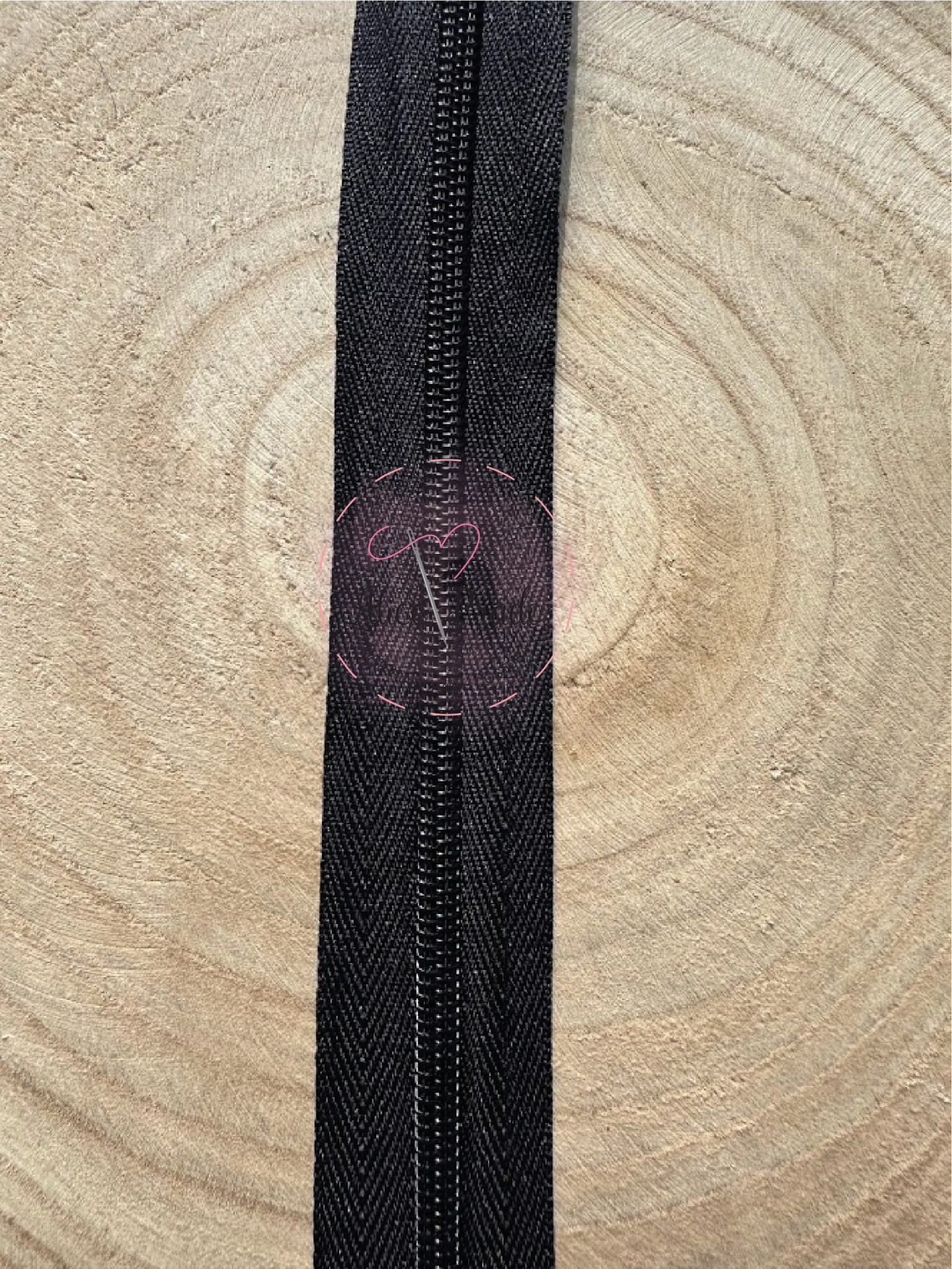 Fecho éclair preto com padrão em espinha de peixe sobre madeira clara