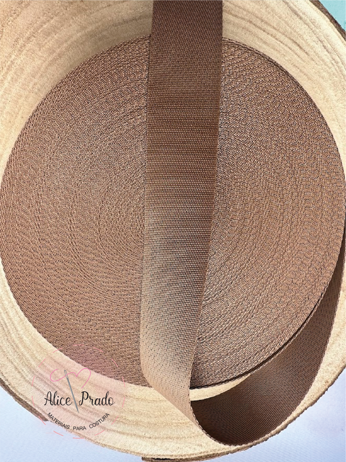 Rolo de fita textil castanha com textura dentro de recipiente cilíndrico claro.