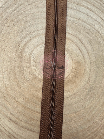 Fecho éclair castanho com padrão ziguezague sobre madeira clara