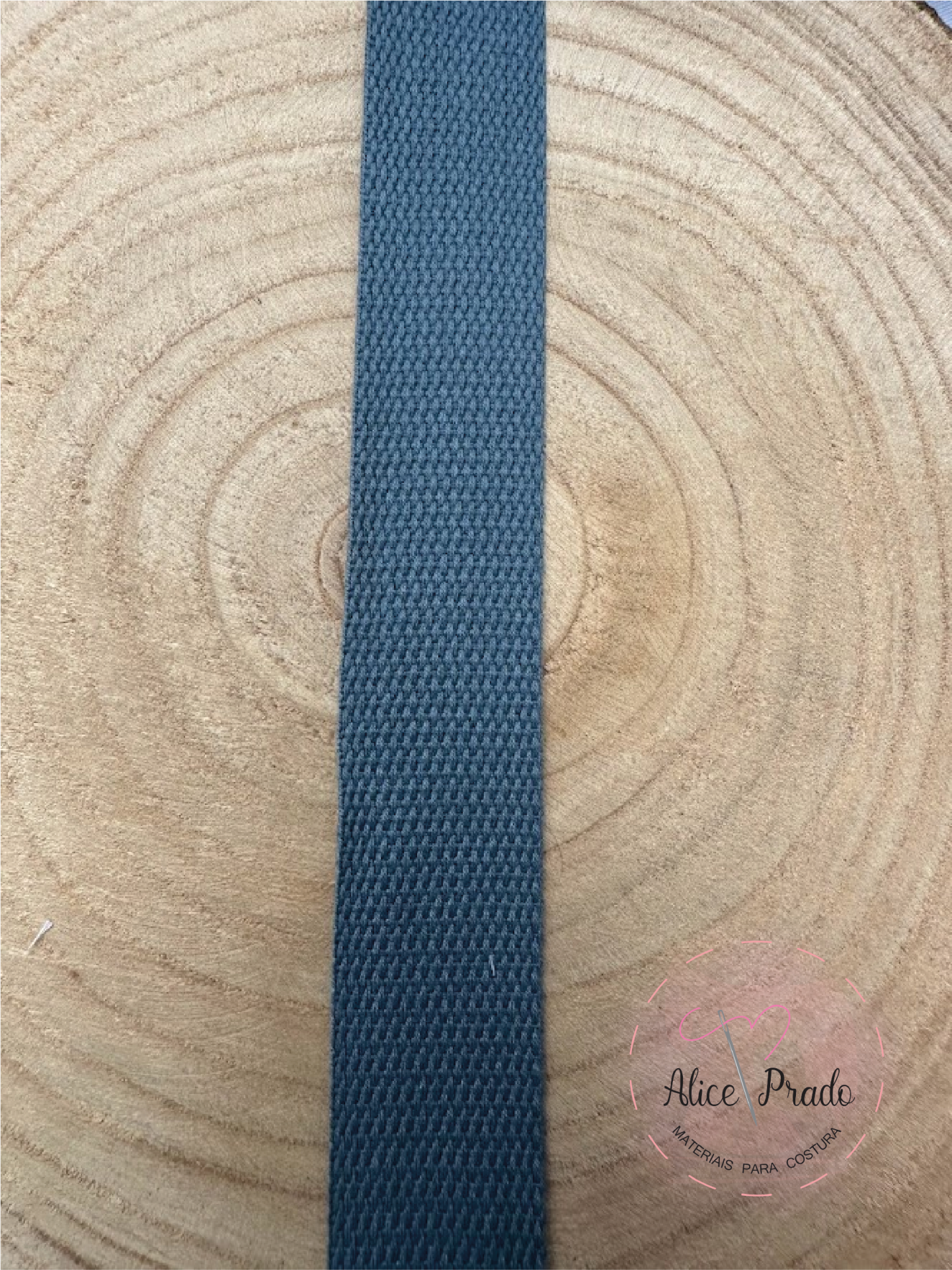 Fita de tecido azul escura com textura entrelaçada sobre madeira clara com anéis