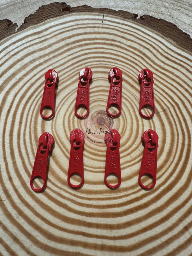 Cursoras de fechar de correr vermelhas sobre madeira com etiqueta 'Alice Prado'