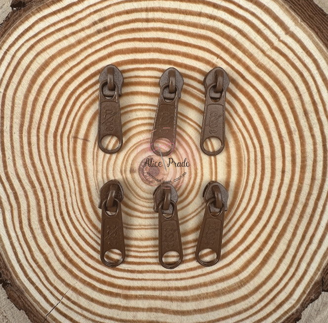 Seis cursores de zíper castanhos escuros sobre superfície com padrão de anéis de árvore