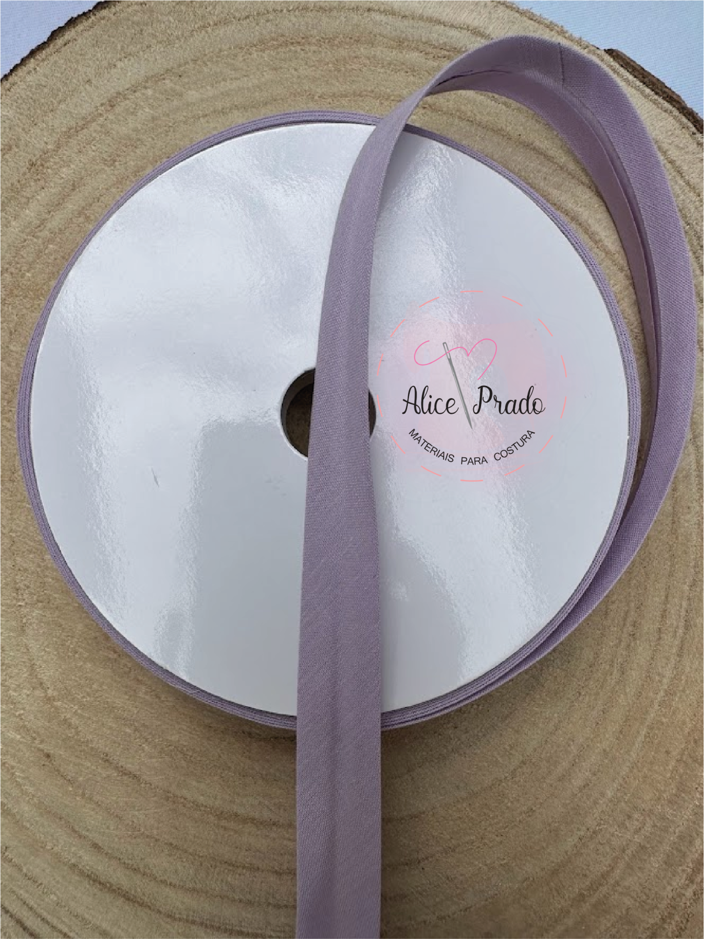 Rolo de fita lilás sobre superfície de madeira com etiqueta central branca