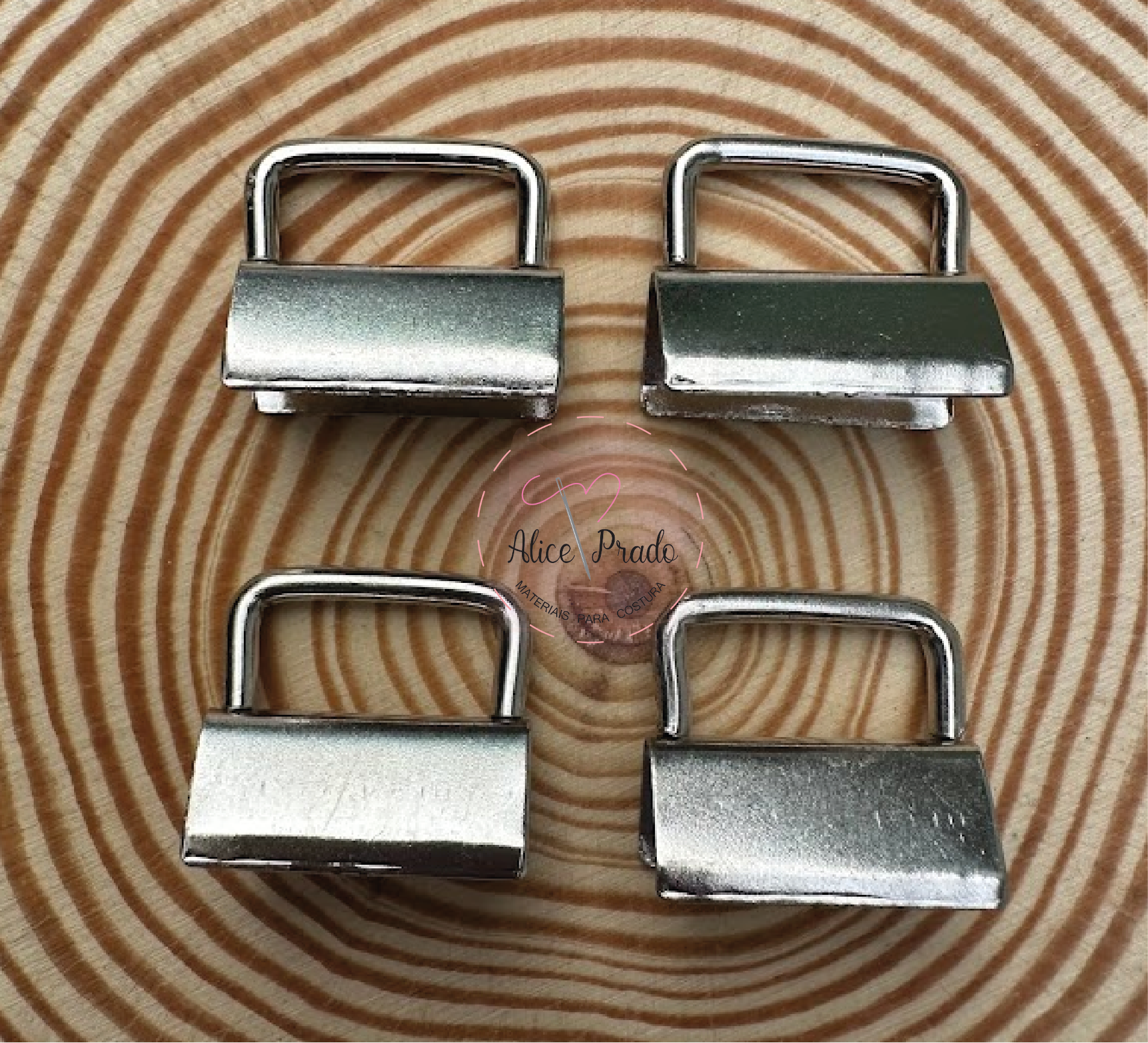 Quatro fechos metálicos prateados sobre superfície de madeira com padrão de anéis