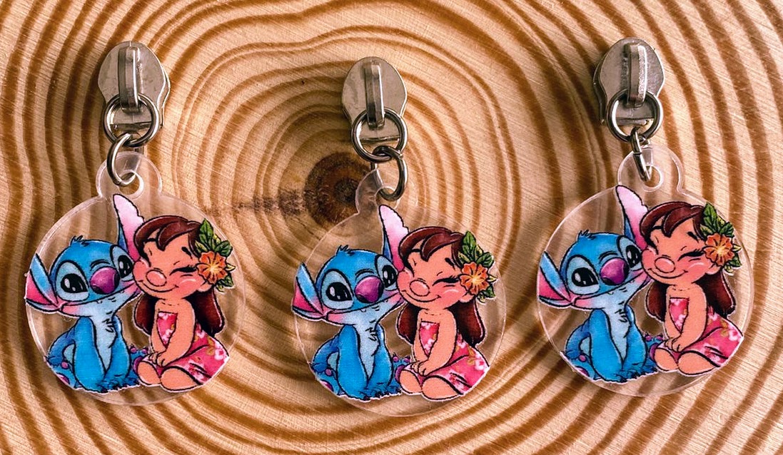 Três porta-chaves com ilustração de personagens coloridos pendurados em madeira clara