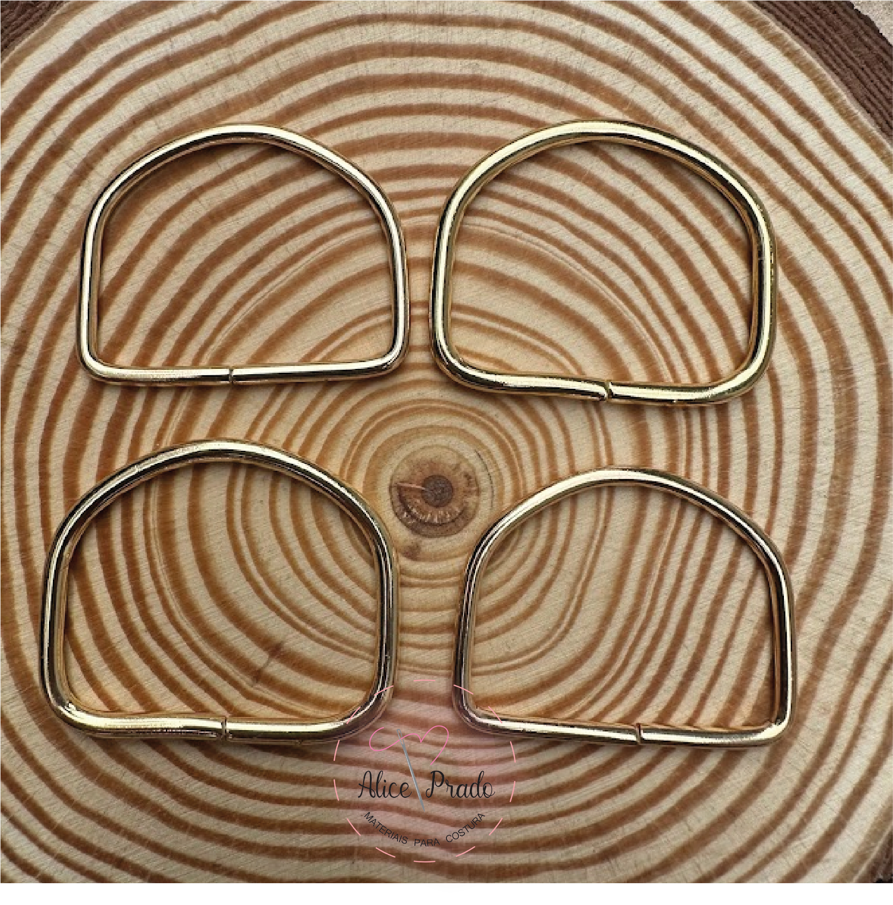 Quatro argolas metálicas douradas sobre superfície de madeira com padrão circular