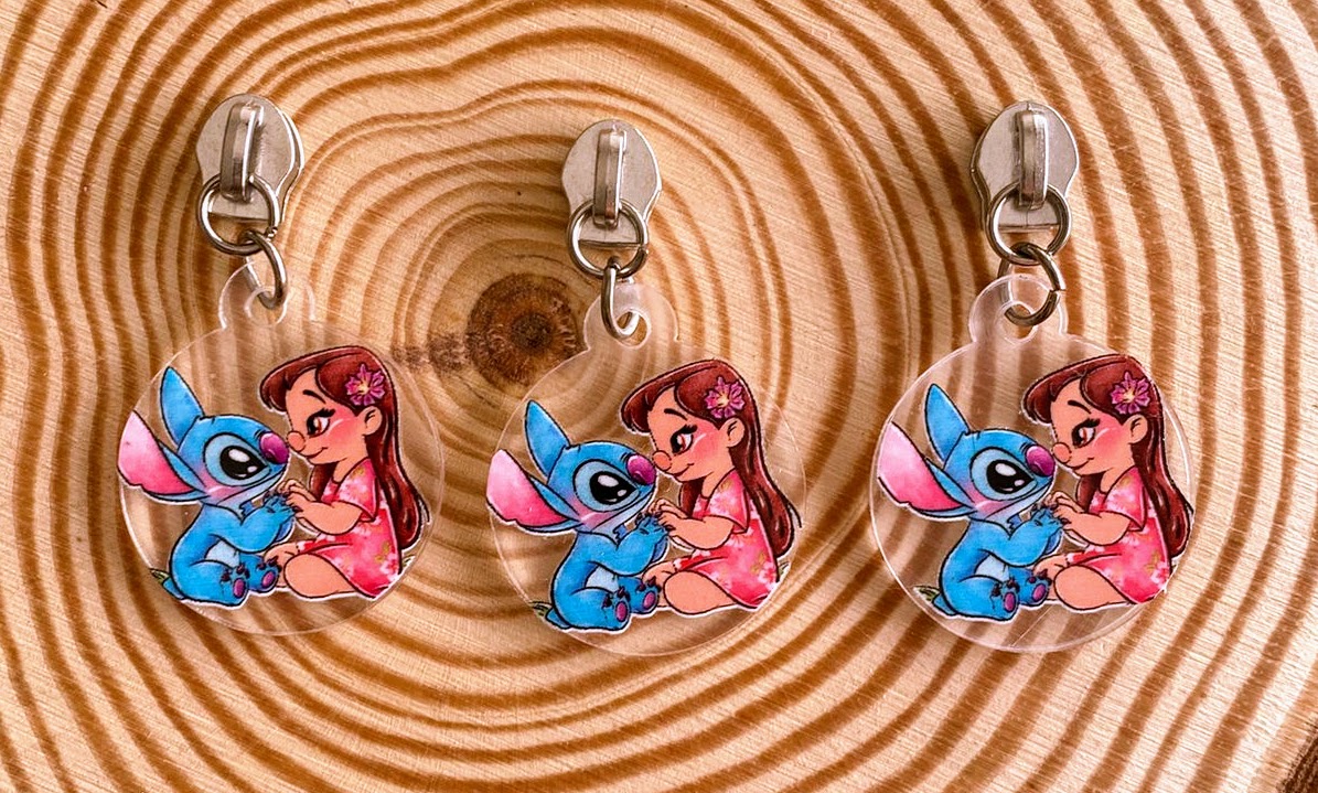 Porta-chaves acrílicos com desenhos de rapariga e personagem azul sobre madeira