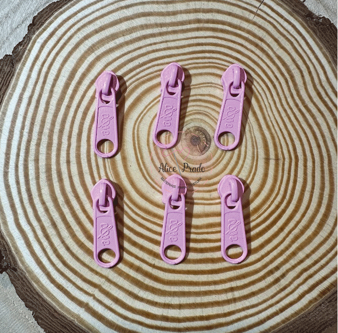 Seis puxadores de fecho éclair cor-de-rosa sobre superfície de madeira com texto