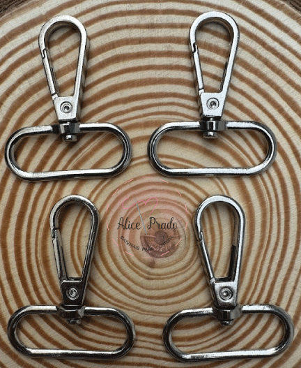 Quatro mosquetões metálicos prateados sobre madeira com padrão de anéis