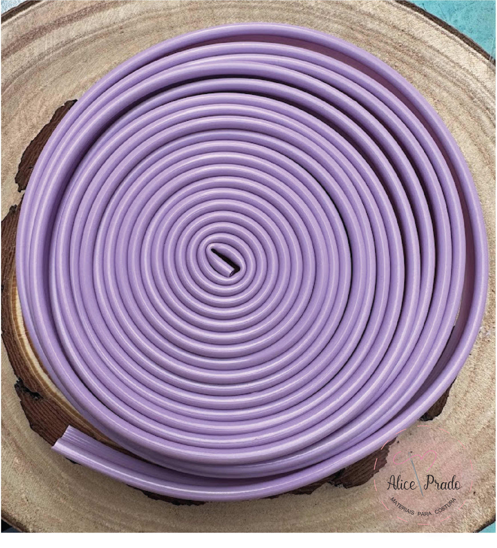 Cordão lilás enrolado em espiral sobre superfície de madeira com texto Alice Prado
