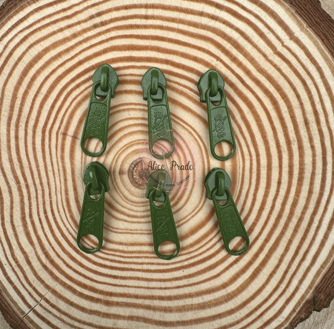 Seis puxadores de fecho verdes sobre superfície de madeira com anéis concêntricos