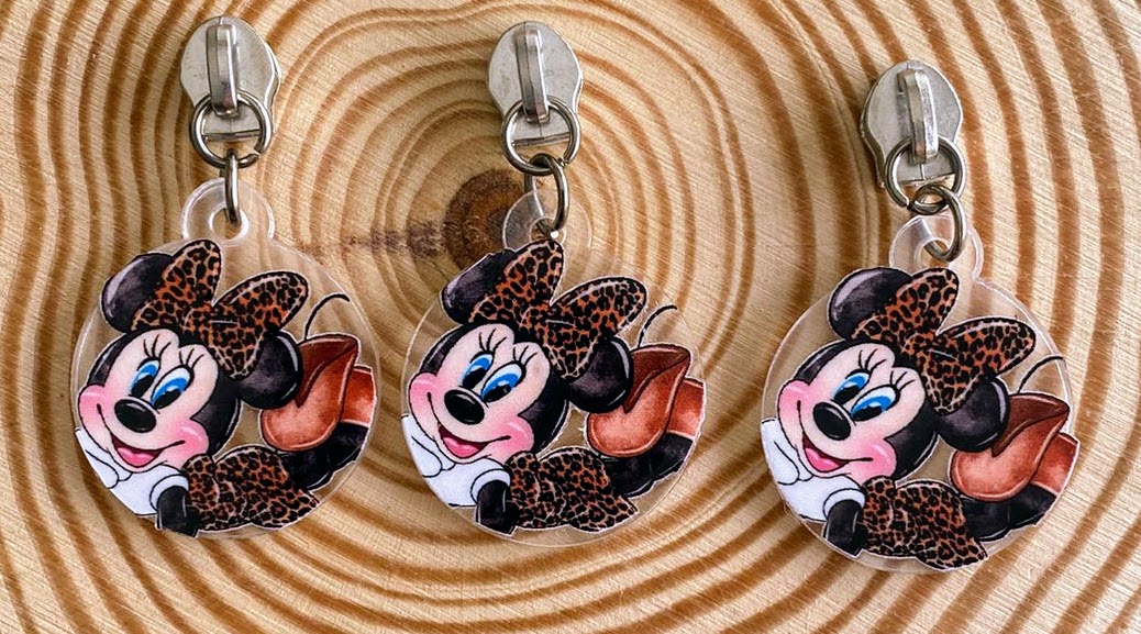 Três chaveiros Minnie Mouse em padrão animal print sobre madeira clara