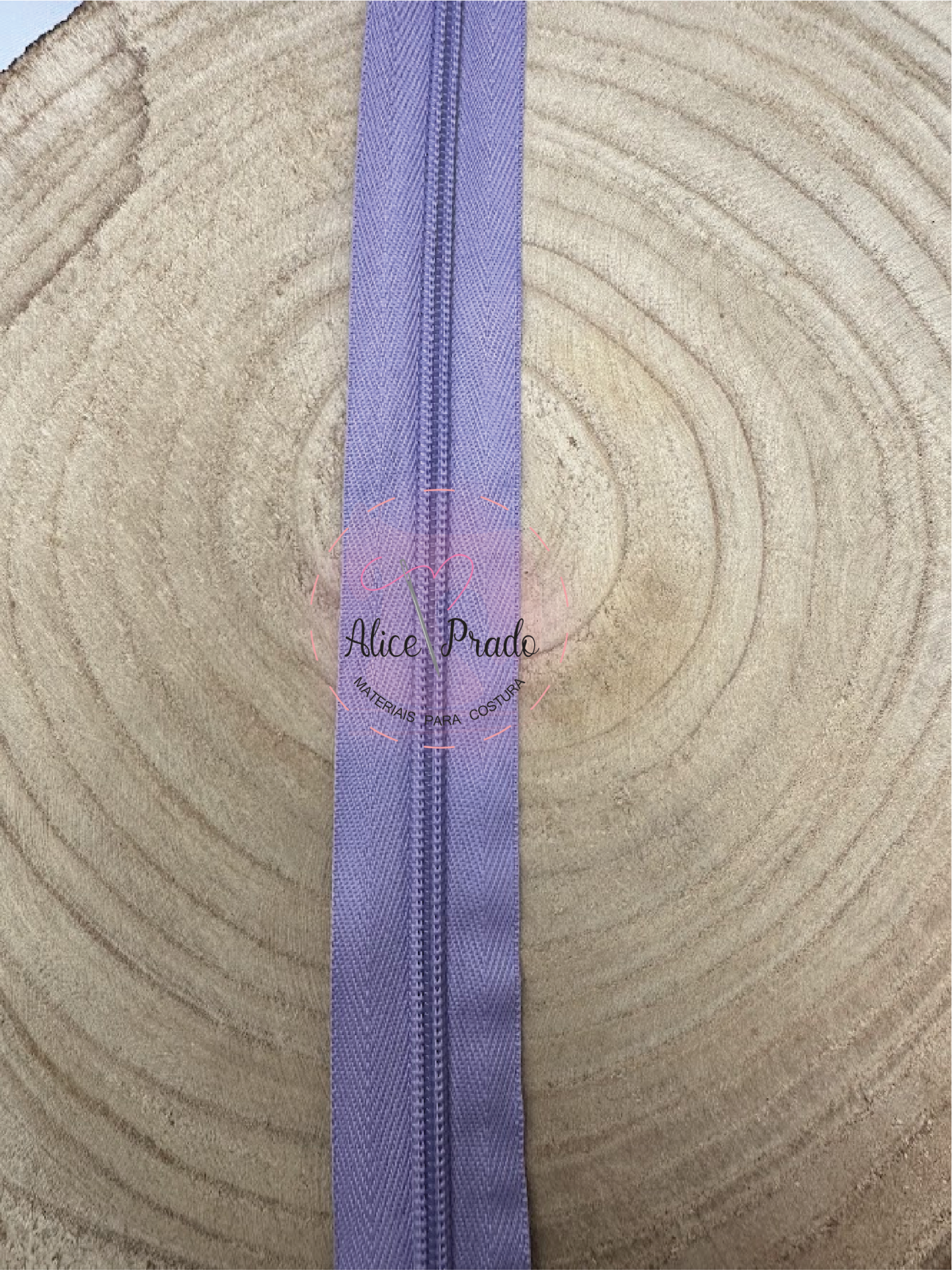 Fecho éclair lilás sobre superfície de madeira com textura concêntrica