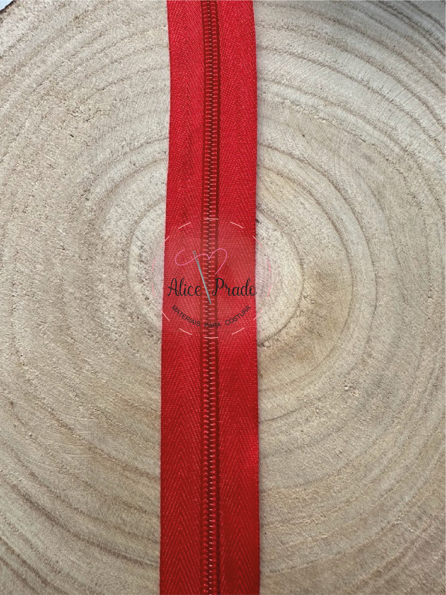 Fita de tecido vermelha com costura central sobre superfície de madeira clara