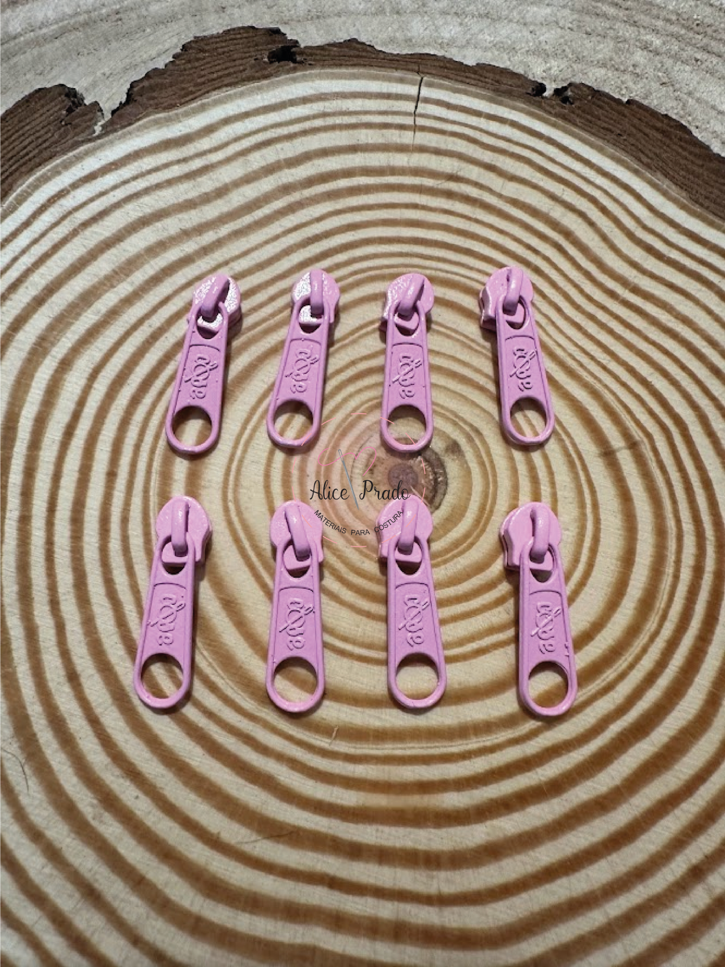 Oito pegas de fecho éclair cor-de-rosa sobre tronco de madeira