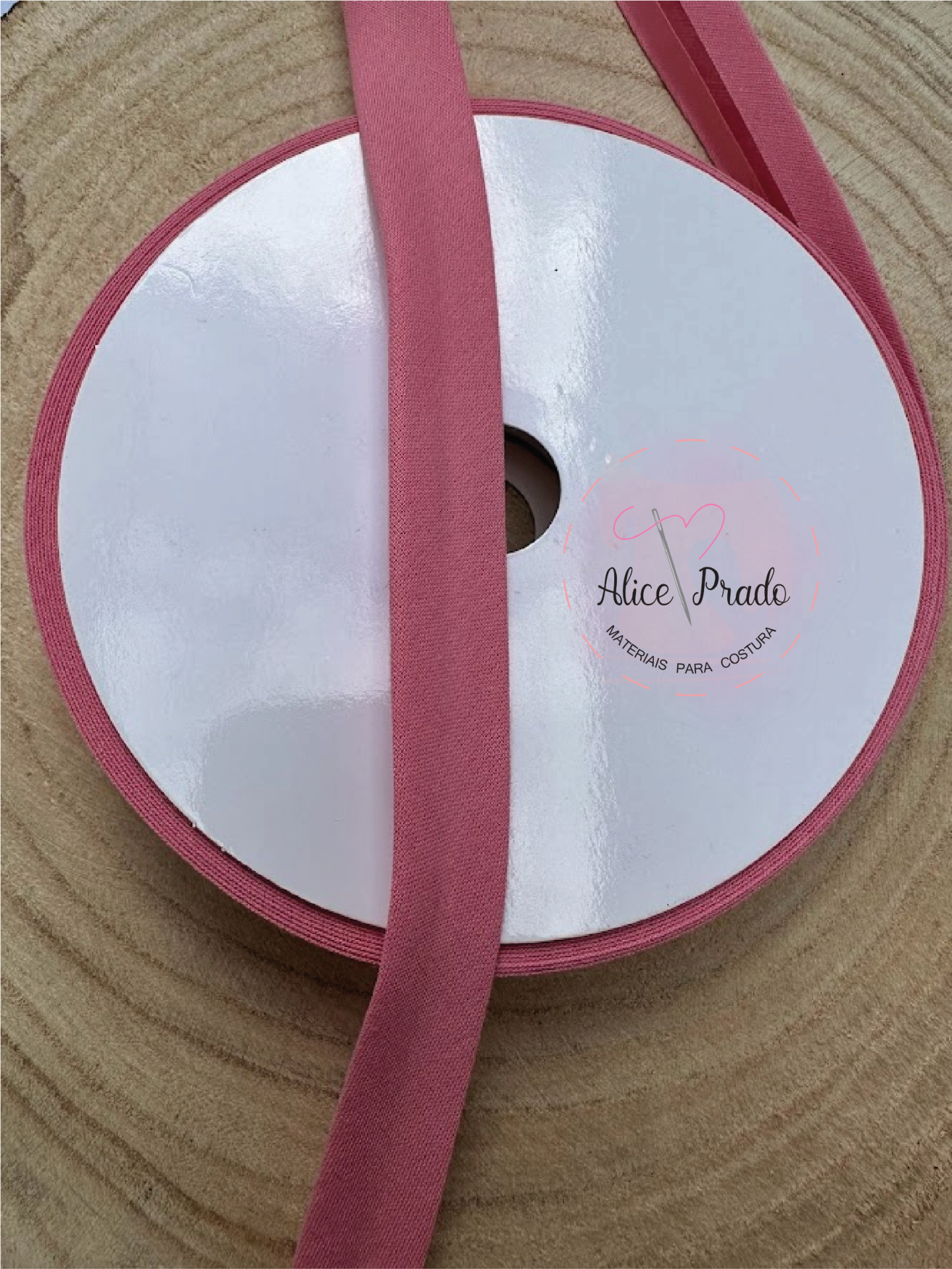 Rolo de fita cor-de-rosa com etiqueta Alice Prado sobre madeira