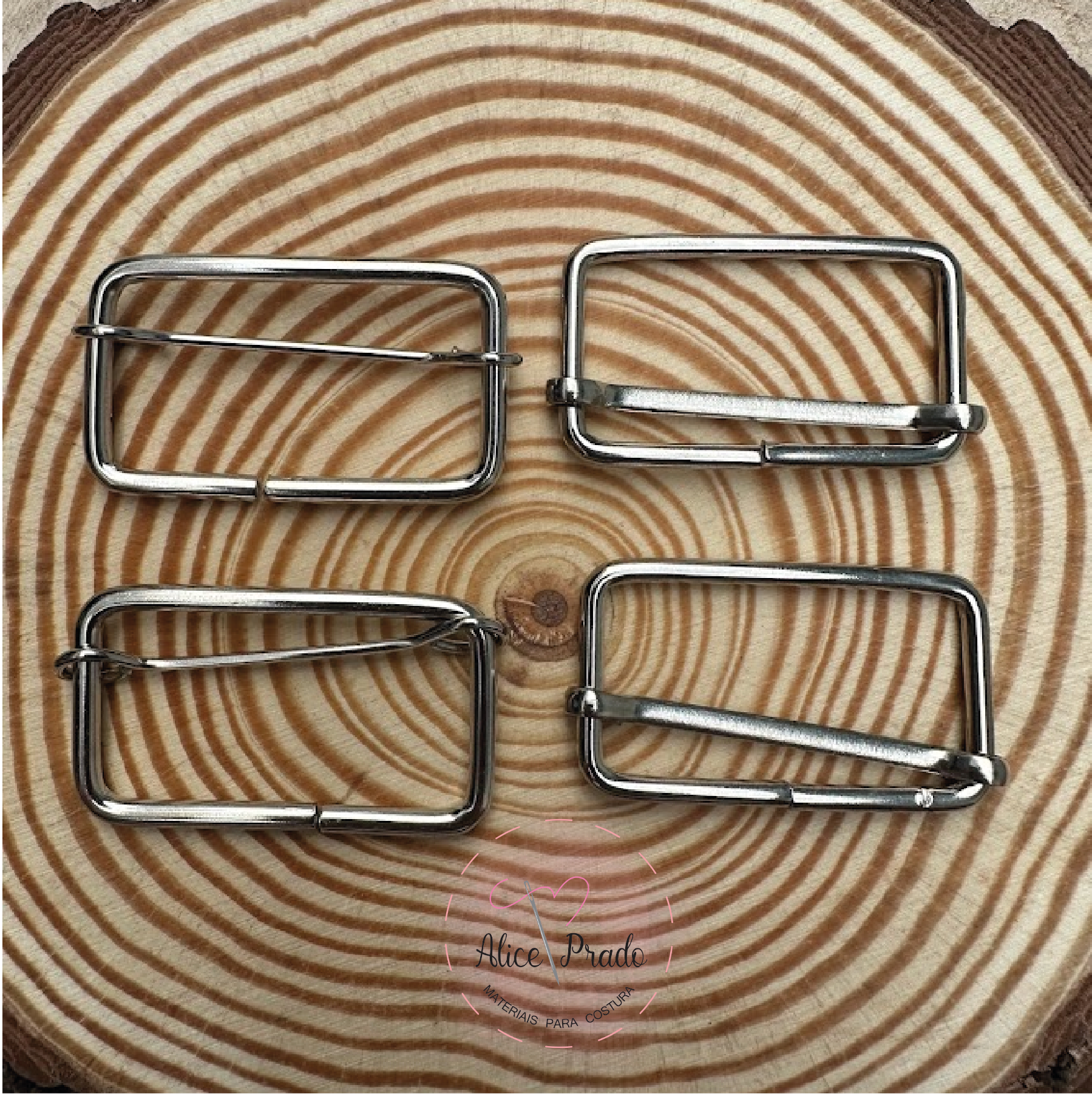 Quatro fivelas metálicas prateadas sobre superfície com padrão de madeira