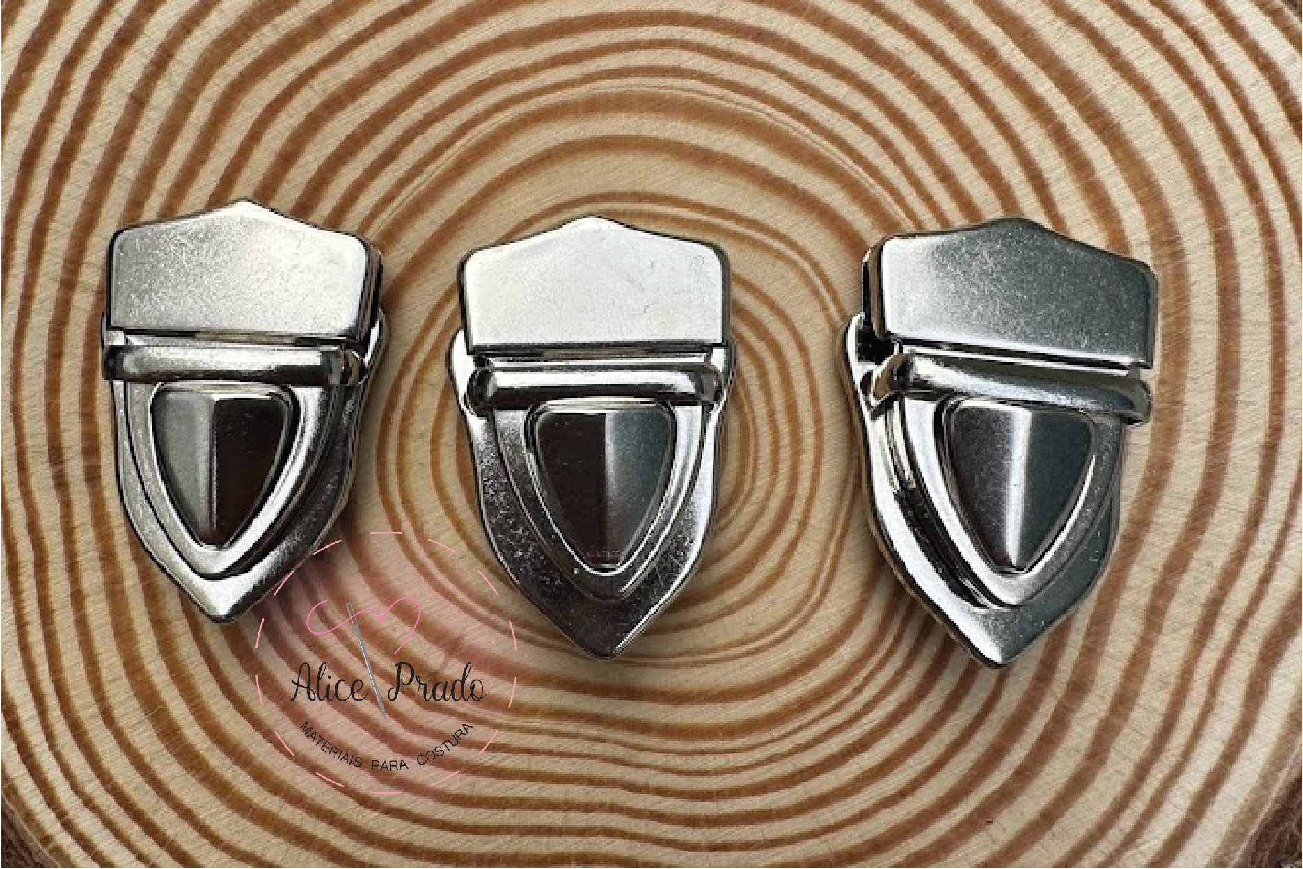 Três fechos metálicos prateados sobre base de madeira com padrão circular