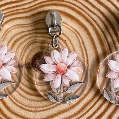 Três porta-chaves com flores cor-de-rosa e folhas sobre madeira