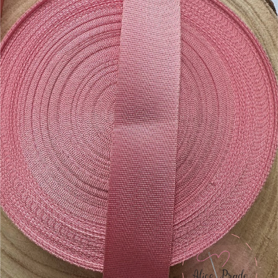 Rolo de fita rosa com textura de malha sobre base de madeira clara