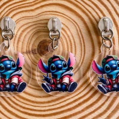 Três chaveiros redondos transparentes com personagem Stitch vestido, pendurados em ganchos sobre madeira