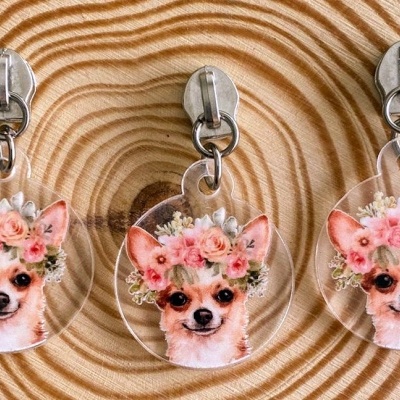 Três porta-chaves com imagem de chihuahuas e coroas de flores sobre madeira